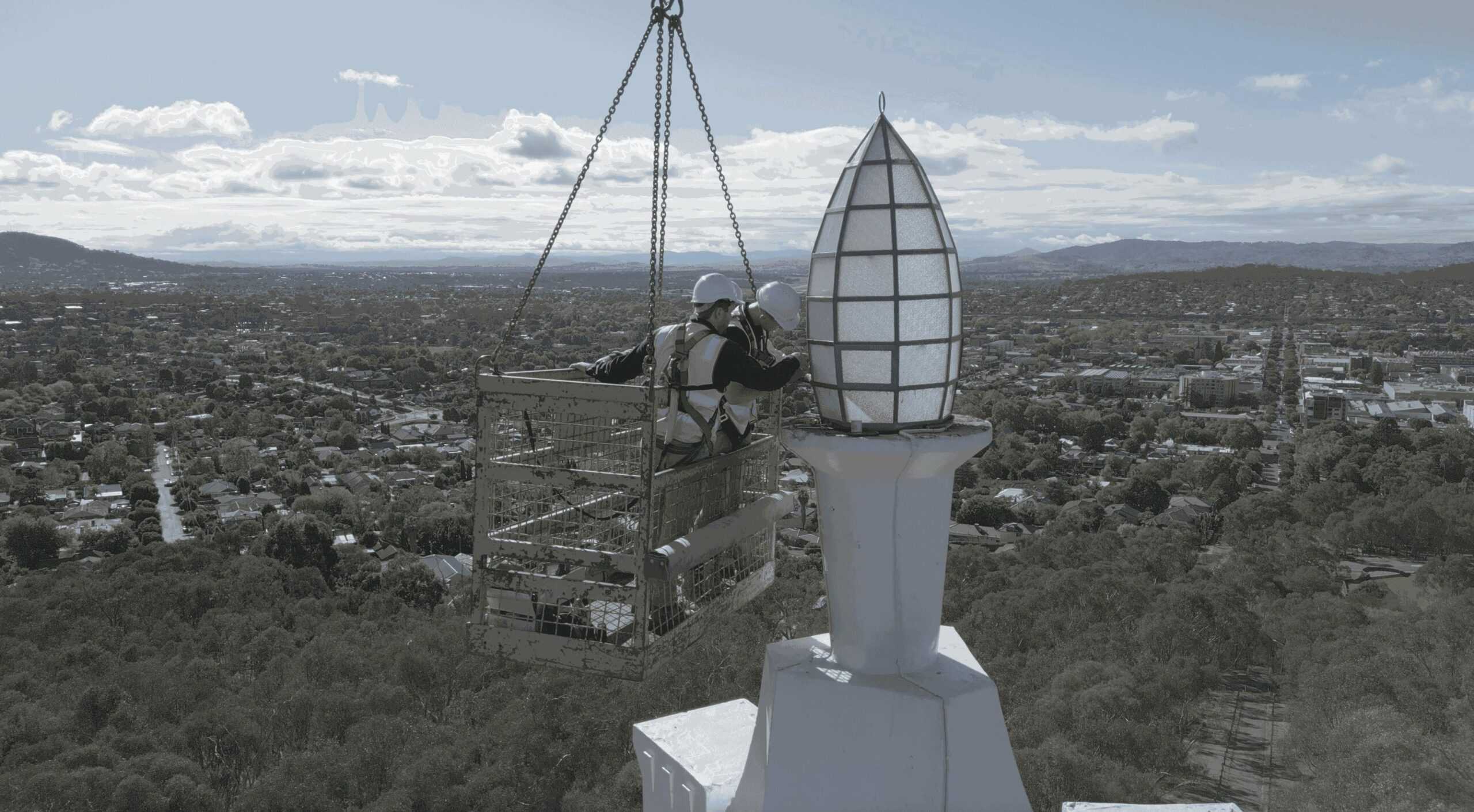 Two Tonkin Group employees changing the globe of the Albury War Memorial.